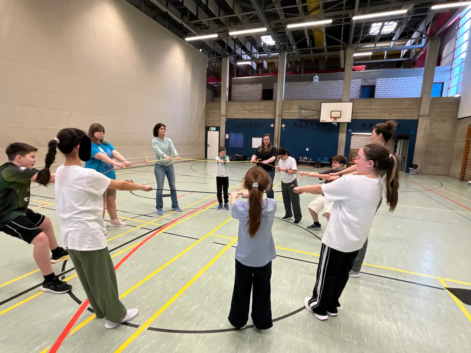Projektwoche: Kinder machen in der Turnhalle eine Übung zur Vertrauensbildung und halten gemeinsam ein Seil fest