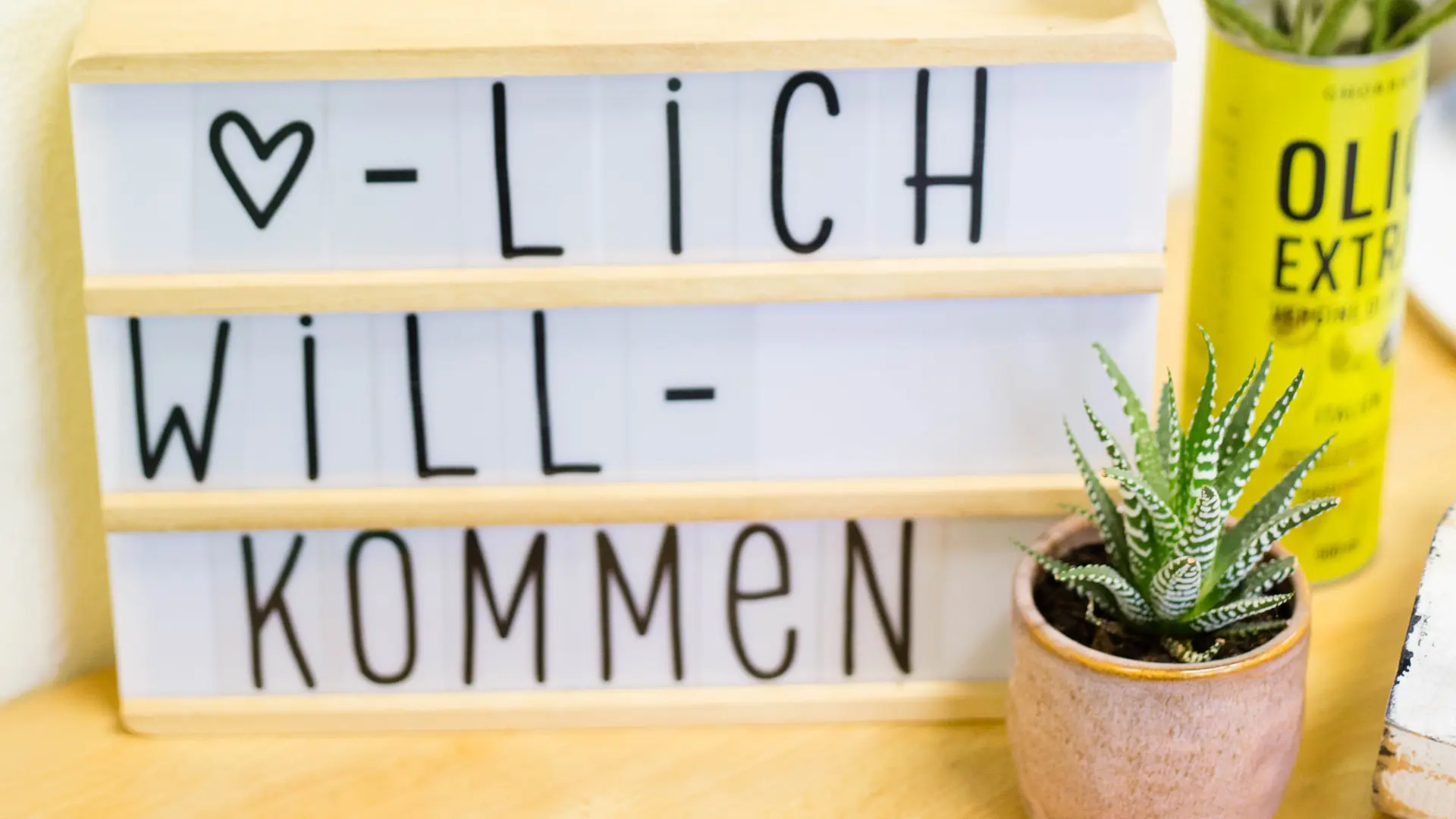 Auf einem Tisch stehen Blumen und eine Tafel mit der Aufschrift Herzlich Willkommen