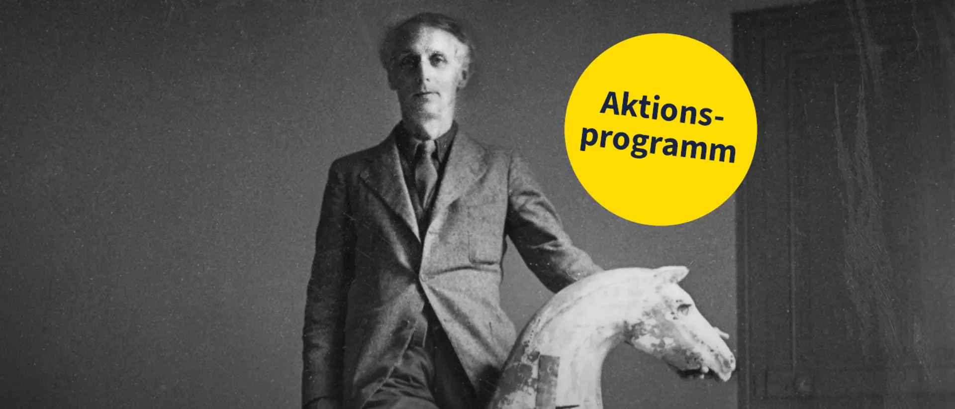 Ein schwarz-weißes Foto von Max Ernst auf einem Schaukelpferd