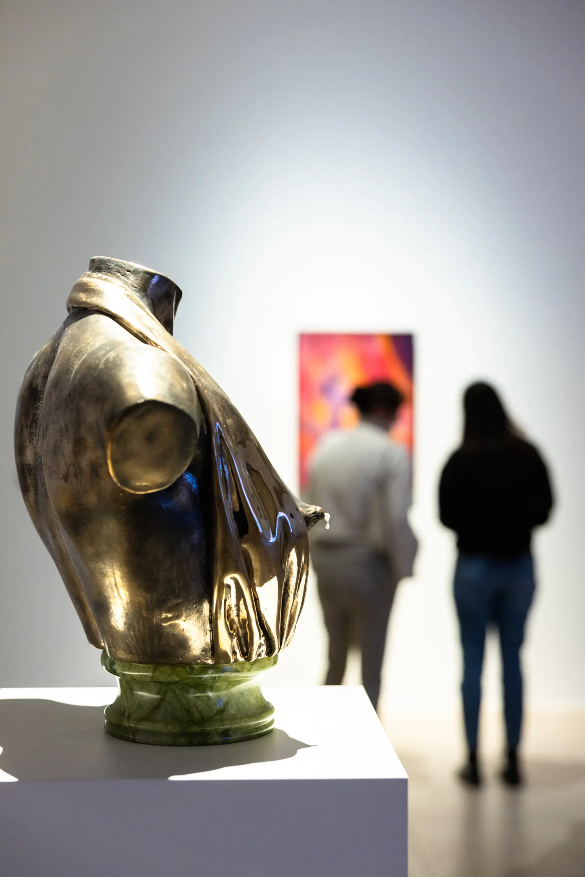 Bronze-Skulptur einer weiblichen Brust mit Besucher*innen im Hintergrund
