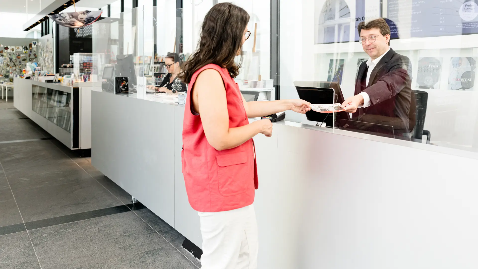 Eine Person kauft am Ticketschalter des Museums eine Eintrittskarte