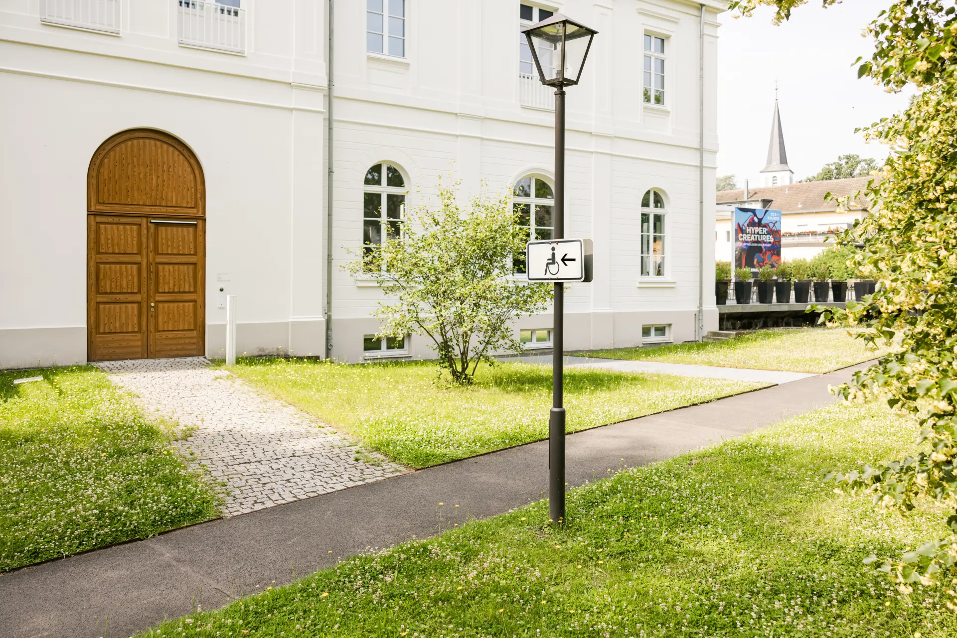 Seiteneingang für Rollstuhlnutzer*innen mit geöffneter Tür und automatischer Türöffnung