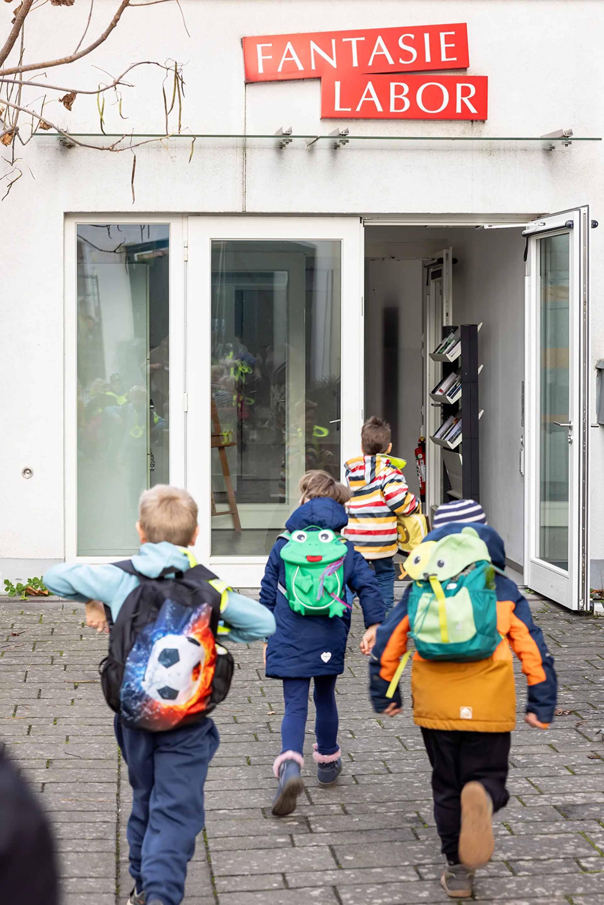 Kinder rennen in ein Gebäude namens Fantasie Labor 