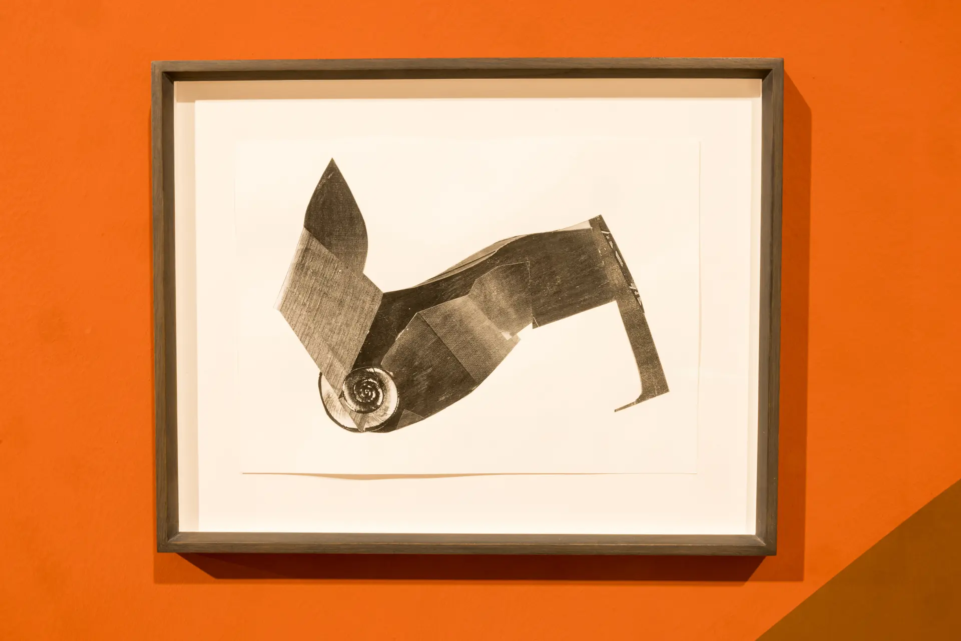 Schwarz-weiße Papiercollage gerahmt auf einer orangenen Wand