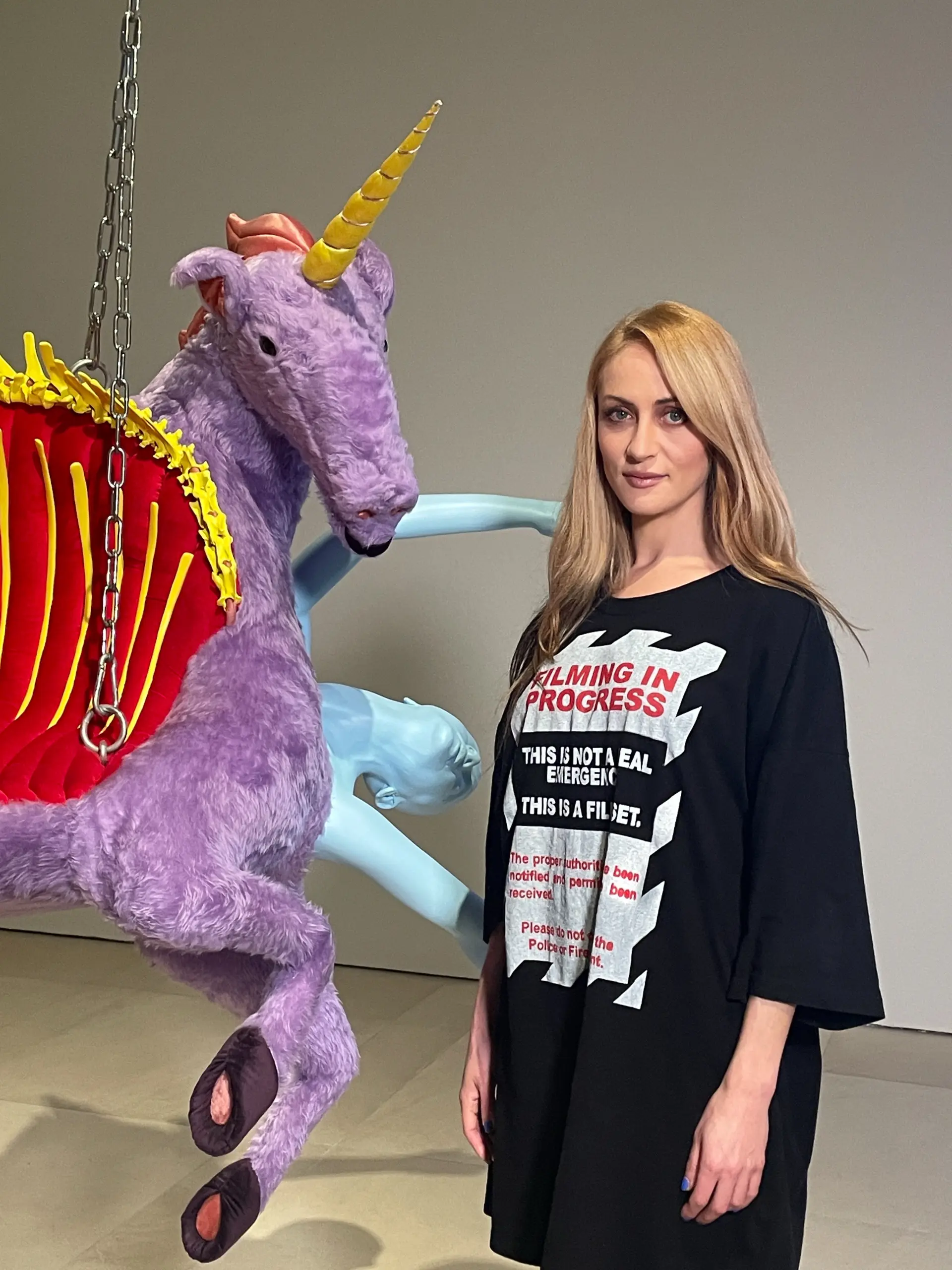 Porträtfoto der Künstlerin neben einer hängenden Einhornskulptur