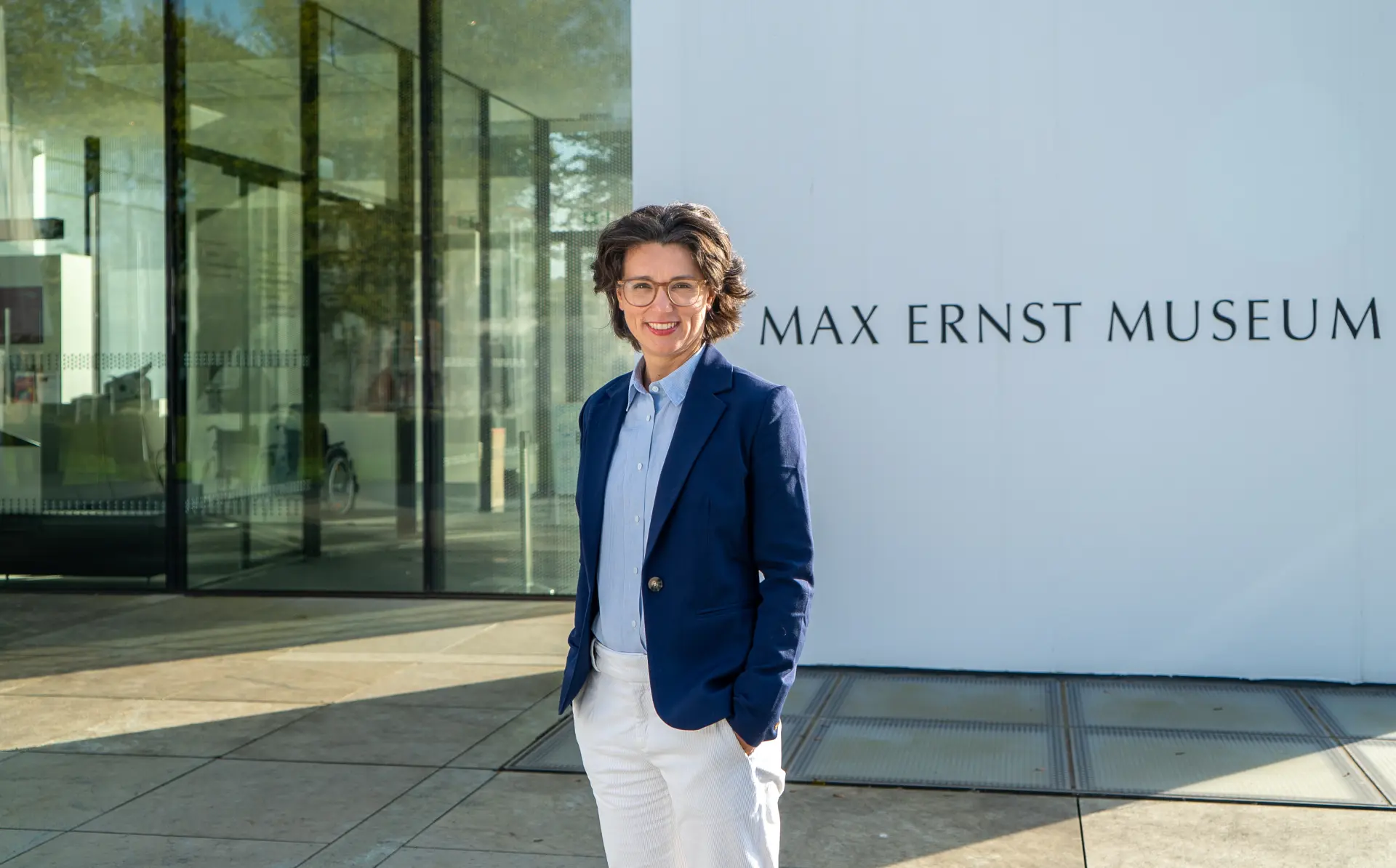 Direktorin Madeleine Frey steht vor dem Museum und lächelt in die Kamera