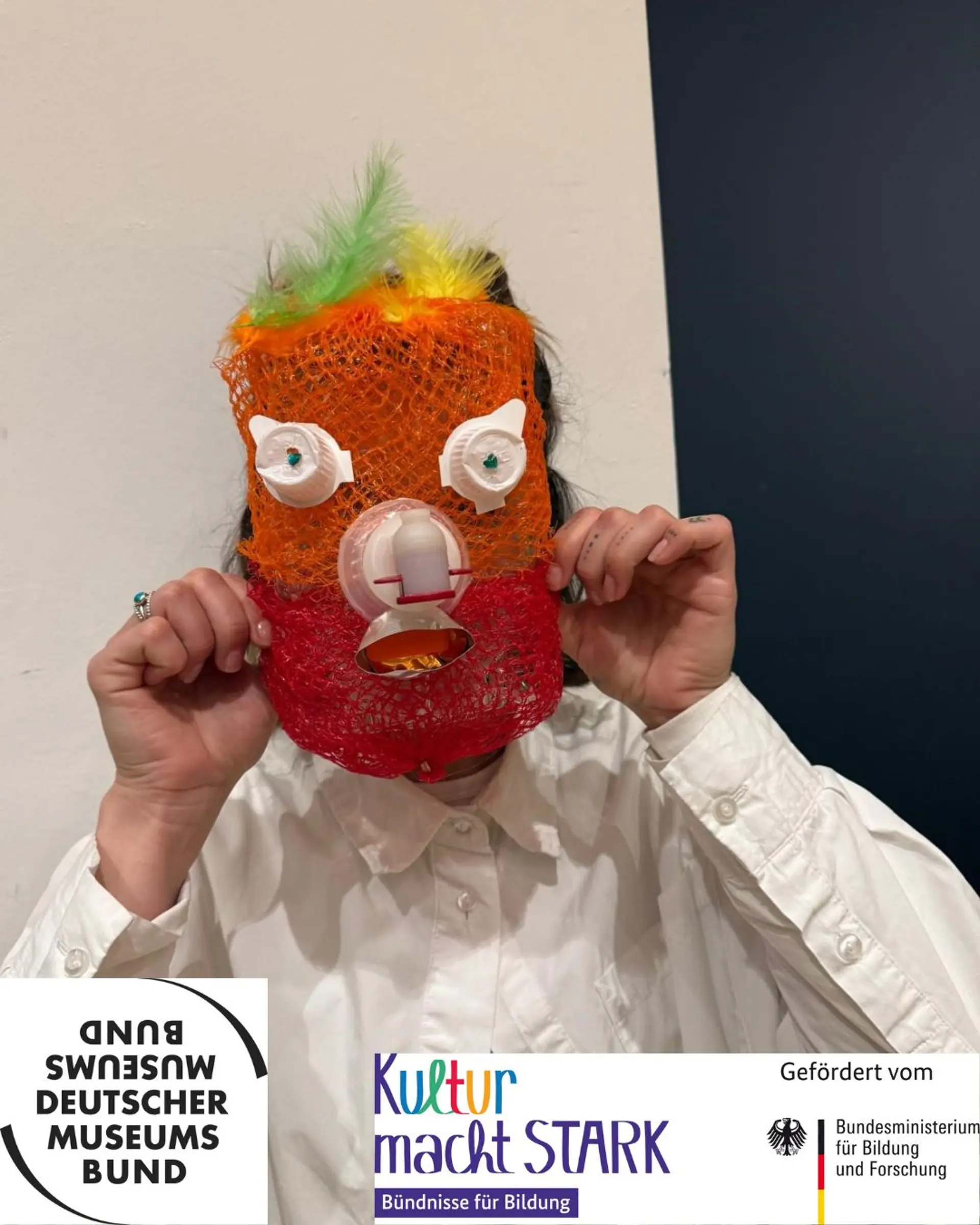 Eine Person hält eine gebastelte Maske vors Gesicht