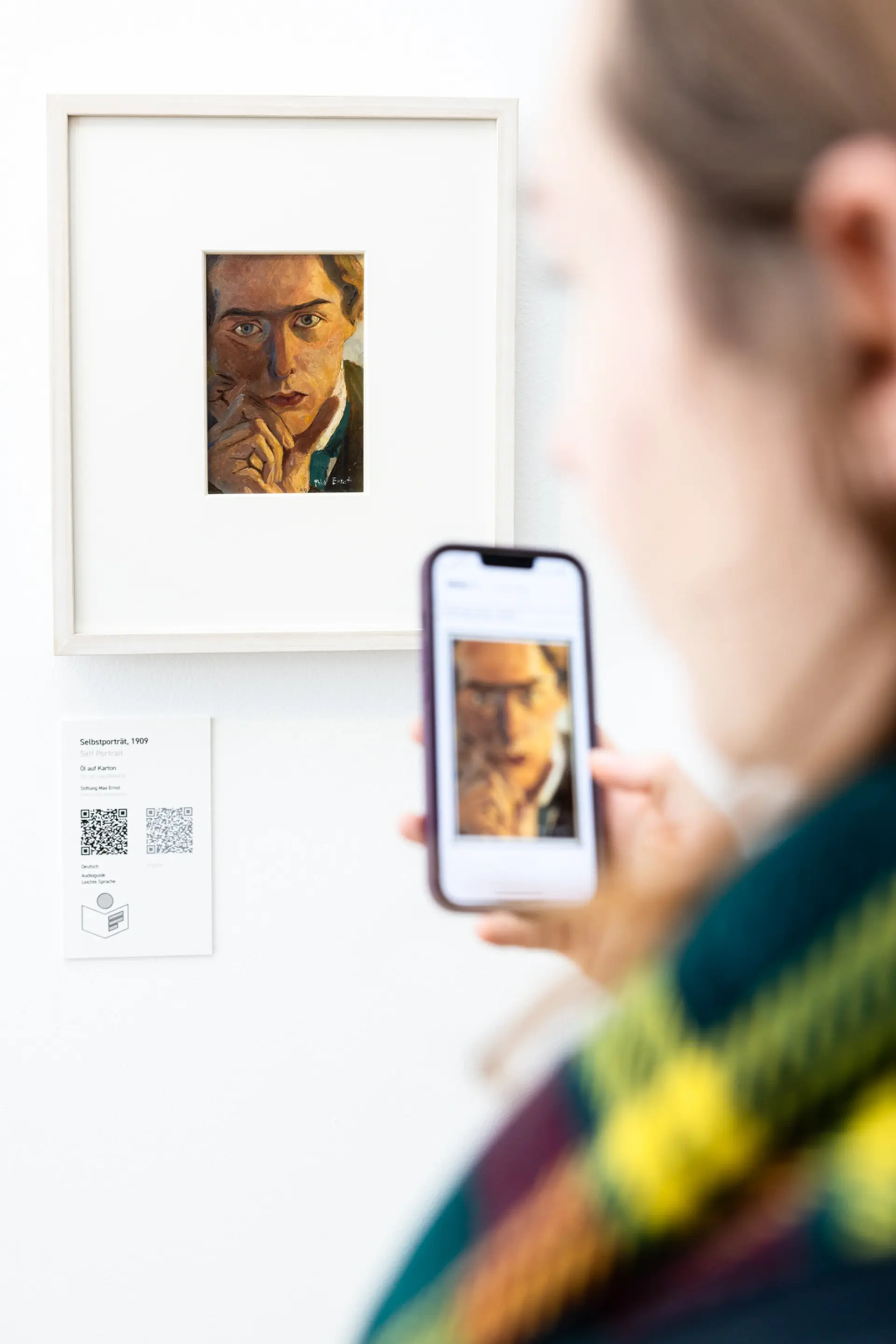 Person scannt mit Handy einen QR-Code an einem Kunstwerk