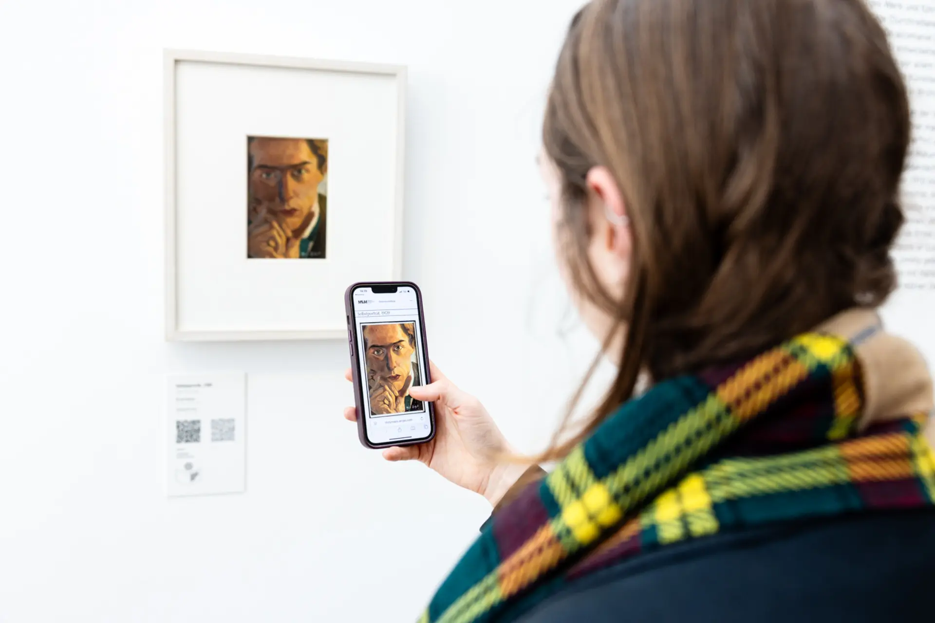 Person scannt mit Handy einen QR-Code an einem Kunstwerk