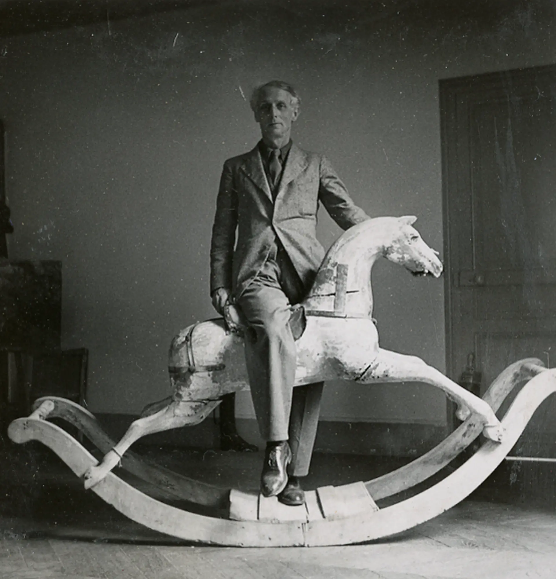 Max Ernst steht über einem Schaukelpferd