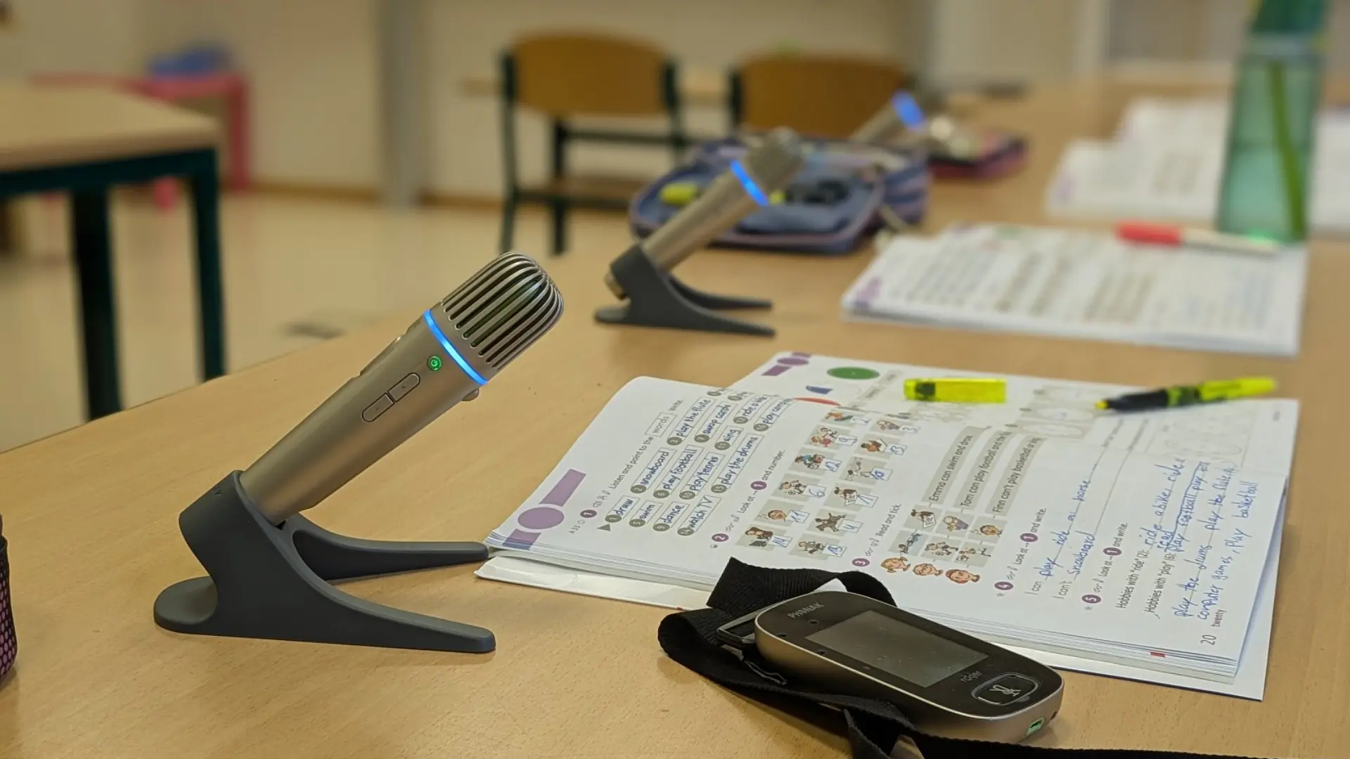 Inklusionsklasse: Lehrerin steht  am Tisch mit vier Kindern im Grundschul-Klassenzimmer. Ein Junge trägt ein Hörgerät.