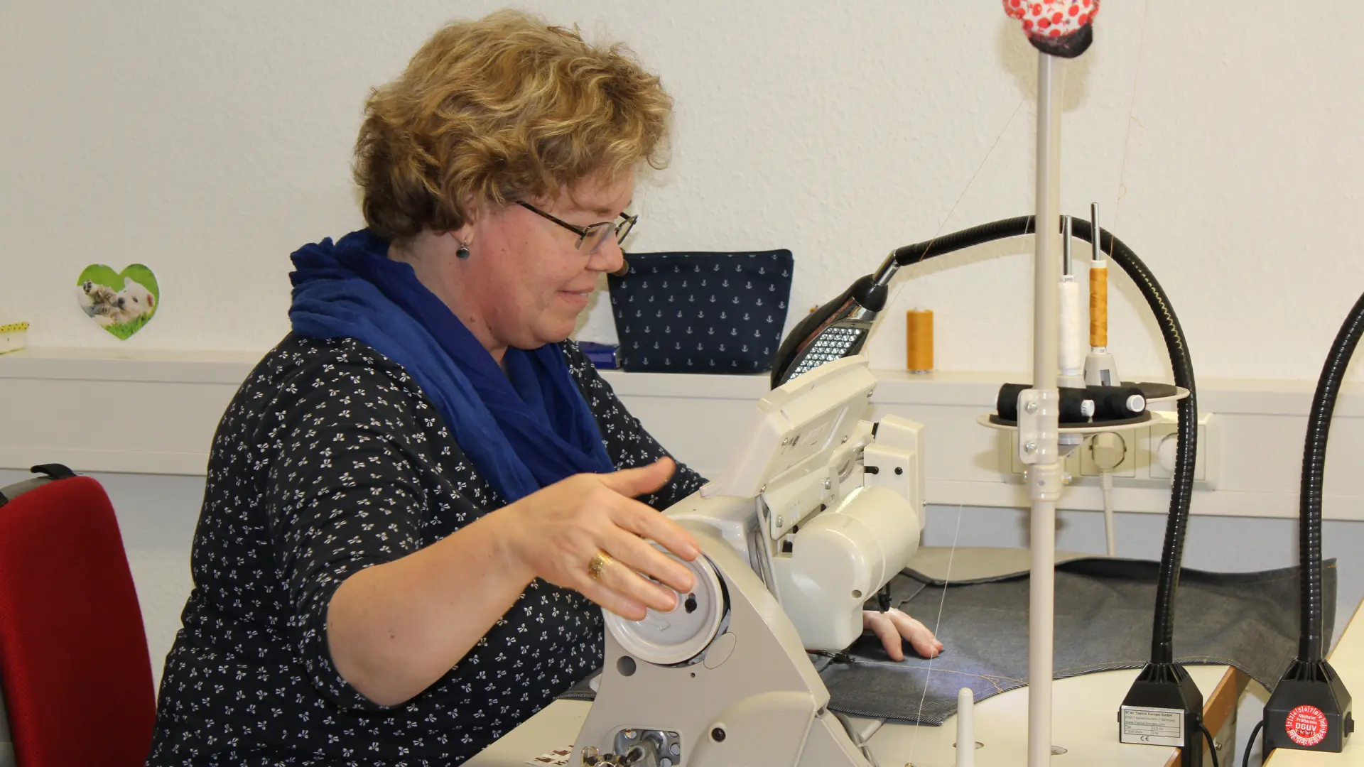 Auf dem Bild ist eine Frau an einer Nähmaschine zu sehen