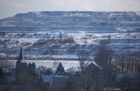 Fotografie eines Dorfes mit historischer Bausubstanz. Im Hintergrund eine Industrielandschaft.