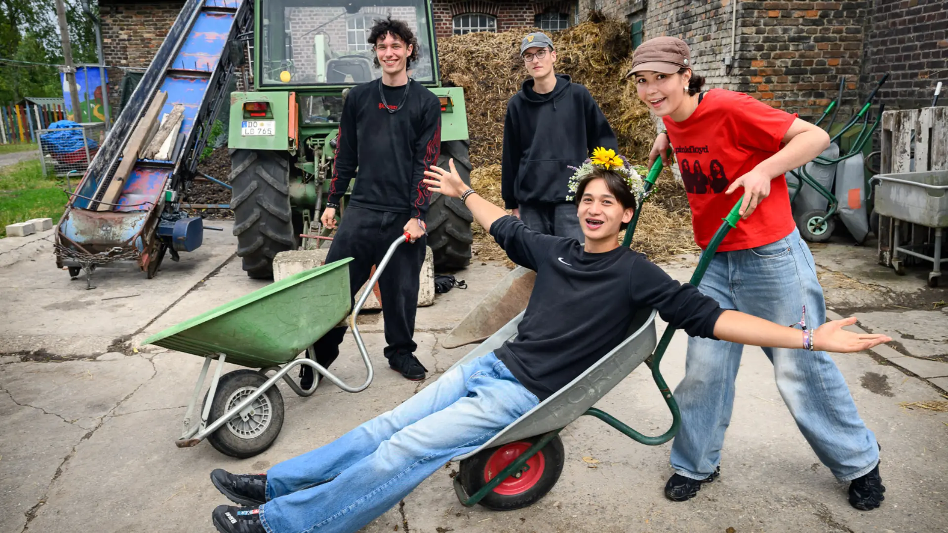 Jugendliche auf einem Bauernhof machen Spaß mit einer Schubkarre 