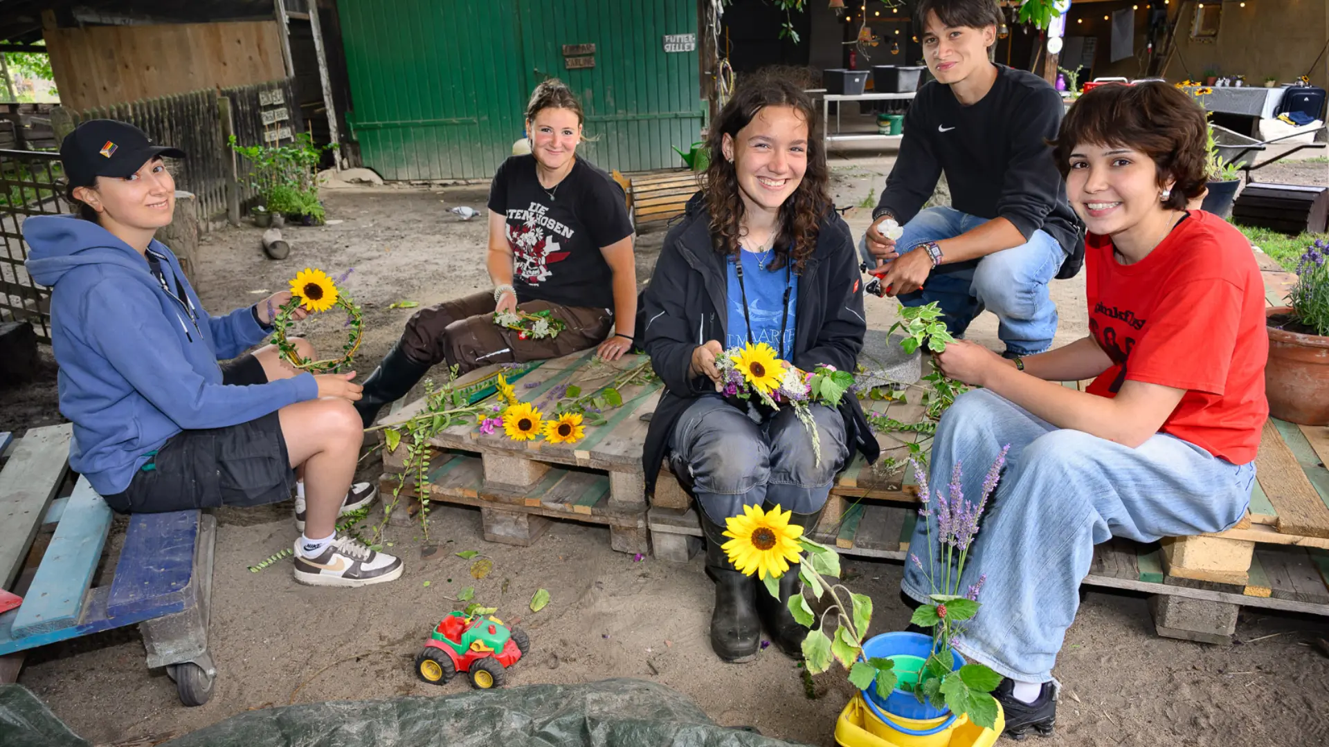 Jugendliche sitzen zusammen und halten Sonnenblumen in den Händen.