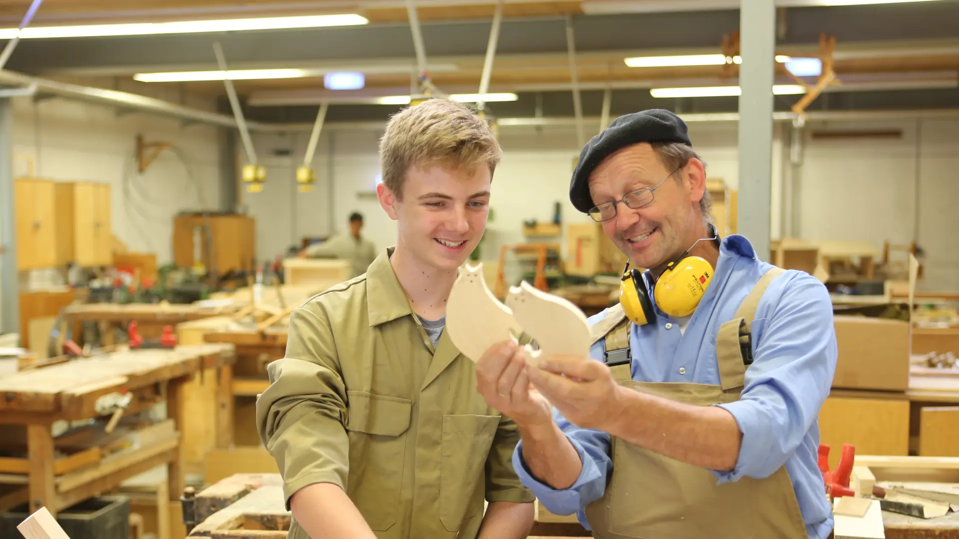 Ein Mann arbeitet gemeinsam mit einem Jugendlichen in einer Holzwerkstatt.