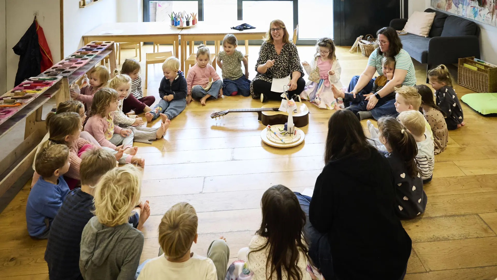 Ein Sitzkreis mit Kindern und einer Erzieherin in der Kita.