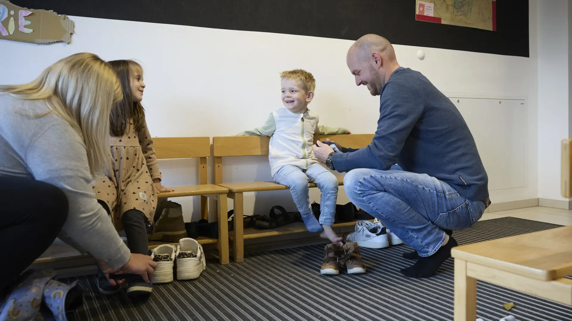 Eltern ziehen ihren Kindern die Schuhe an.