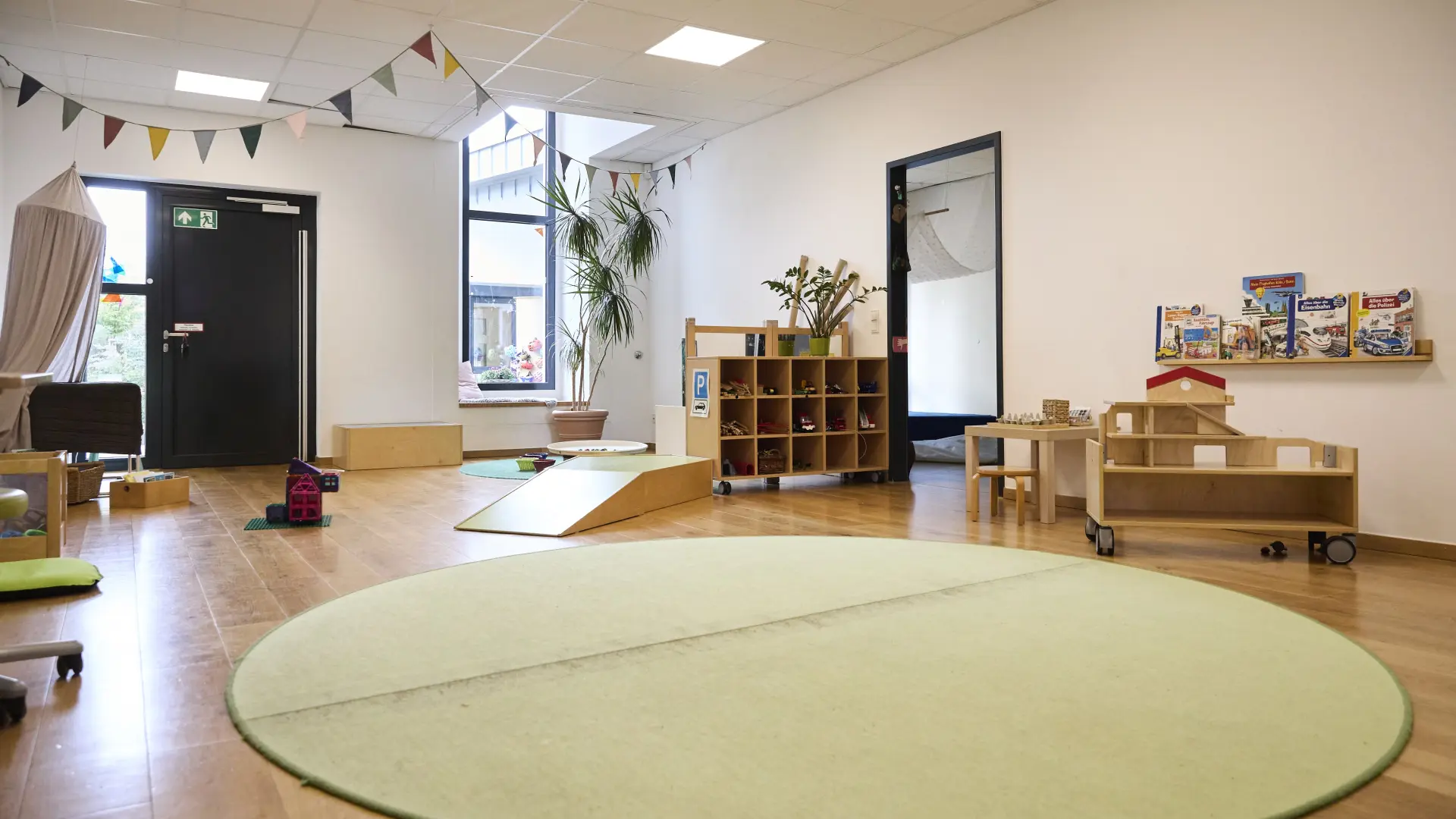 Ein großer Raum mit Spielzeug und Teppich in einer Kita.