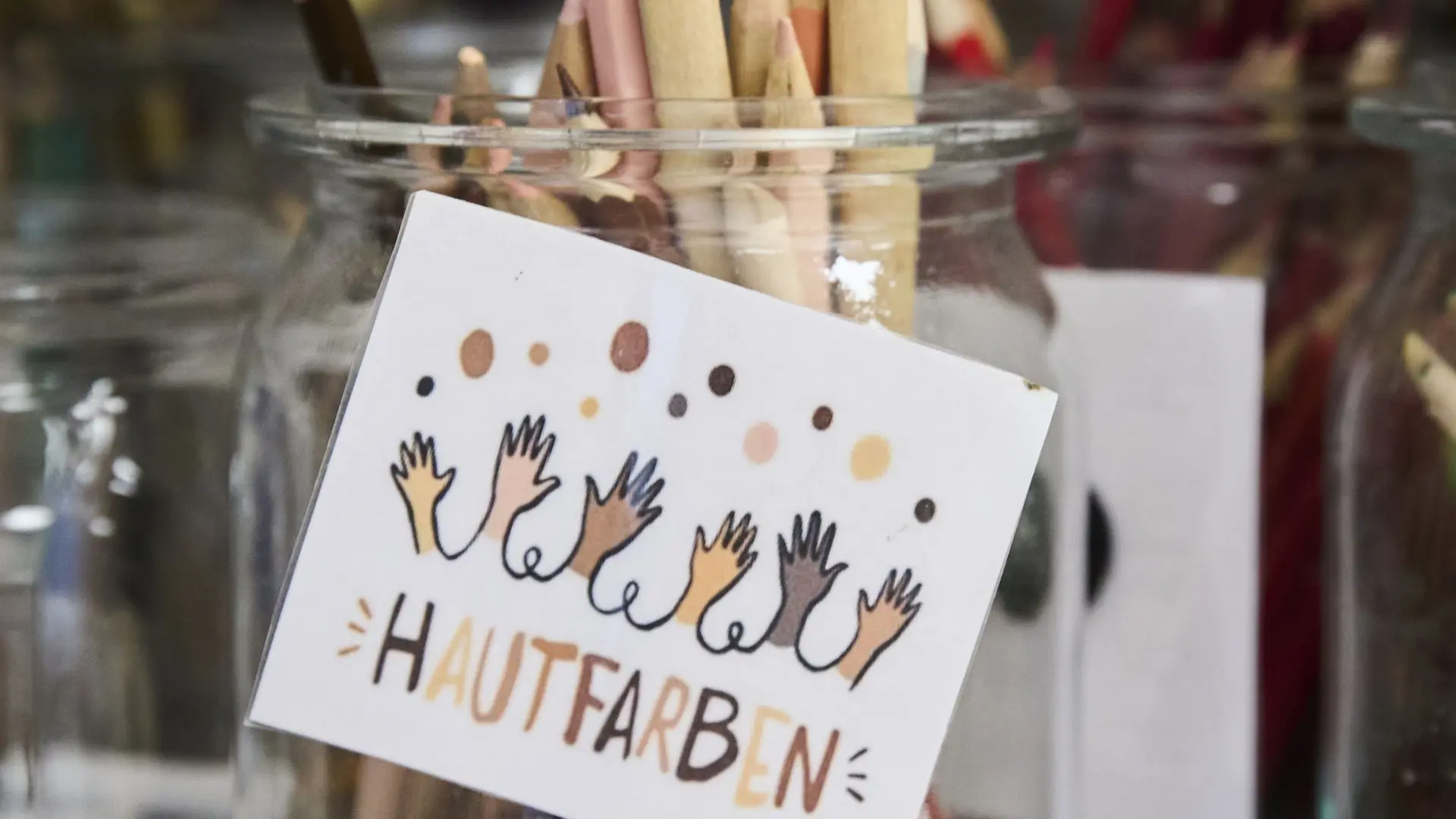 Ein Glas mit Buntstiften. Darauf steht "Hautfarben".