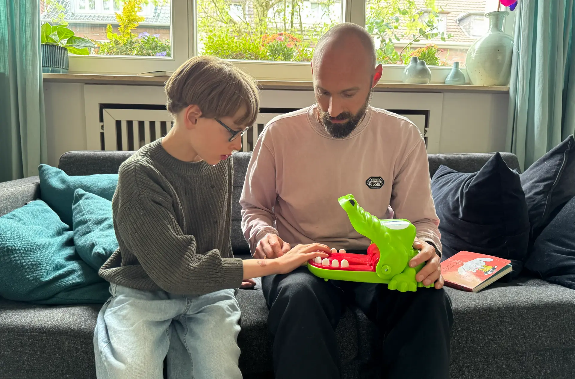 Mateo spielt mit seinem Vater und hält ein Krokodil in der Hand.