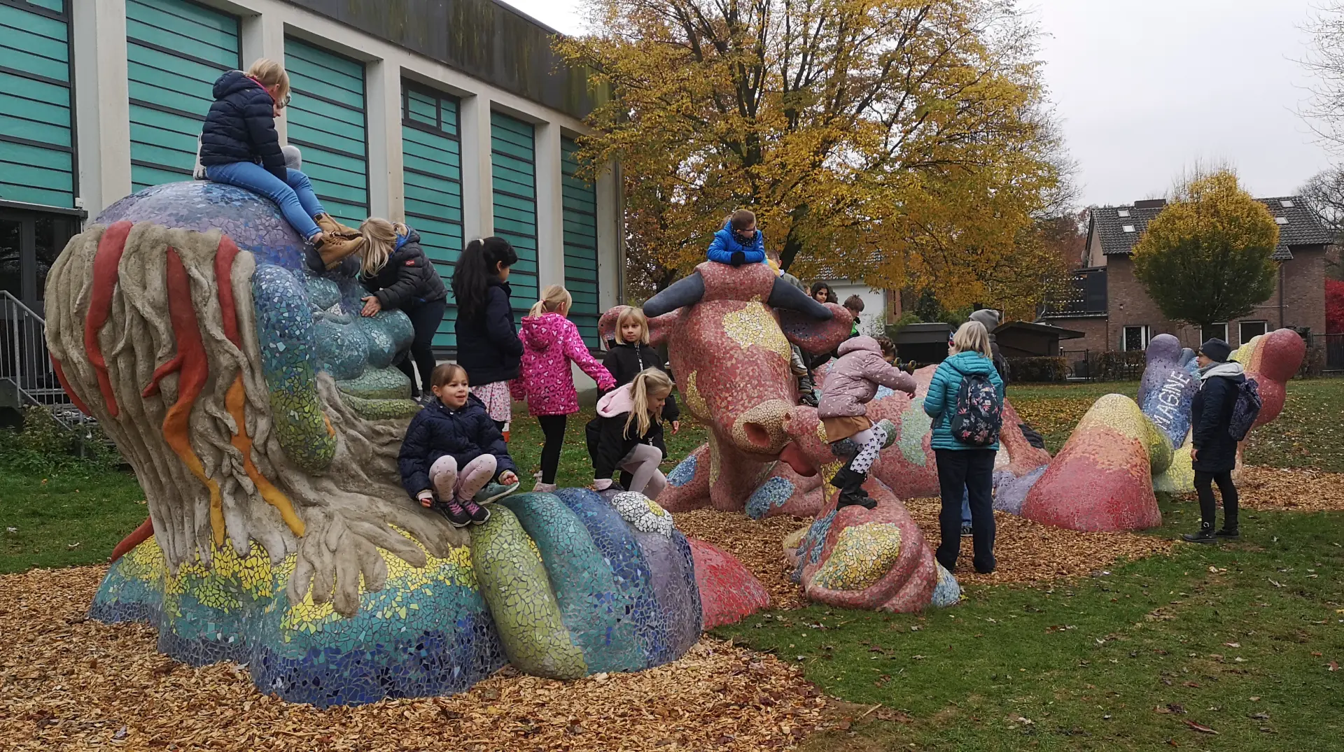 Kinder spielen und klettern auf einer bunten Großskulptur herum.