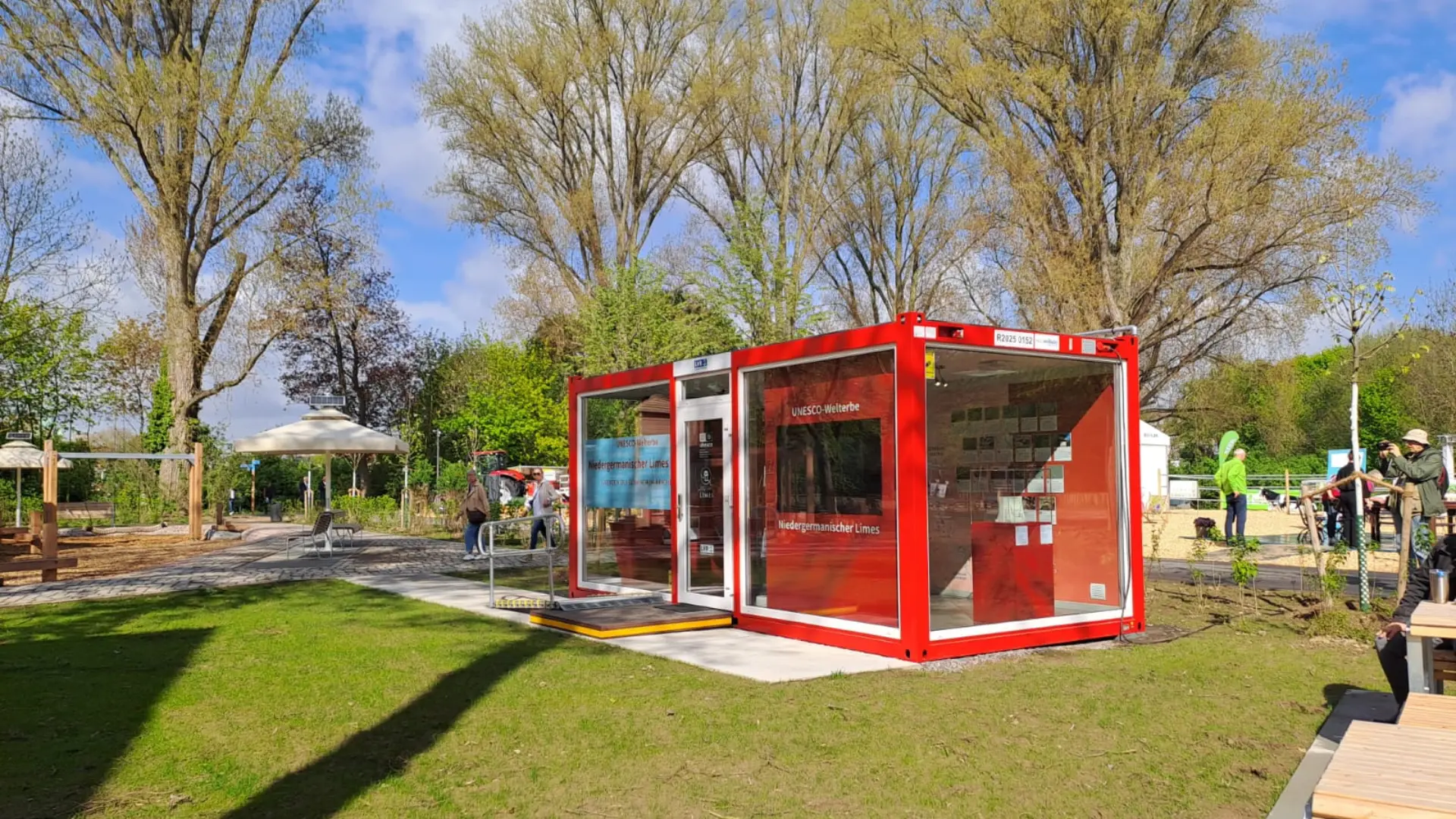 Foto: ein roter Container steht auf einer bepflanzten Grünfläche