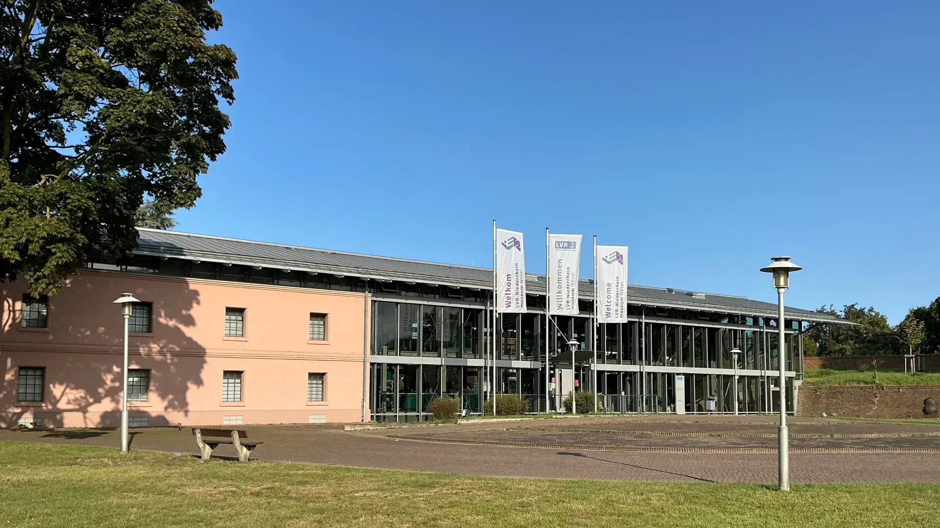 Foto: Großes Gebäude aus rotem Bachstein mit einem historischen PKW im Vordergrund