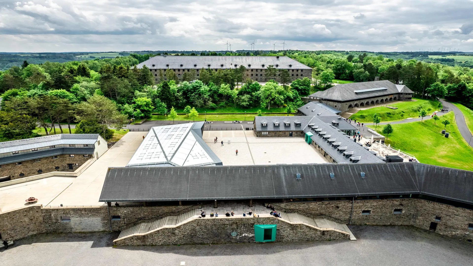 Foto: Mehrere große Gebäude eingebettet in eine Landschaft mit viel Wald.