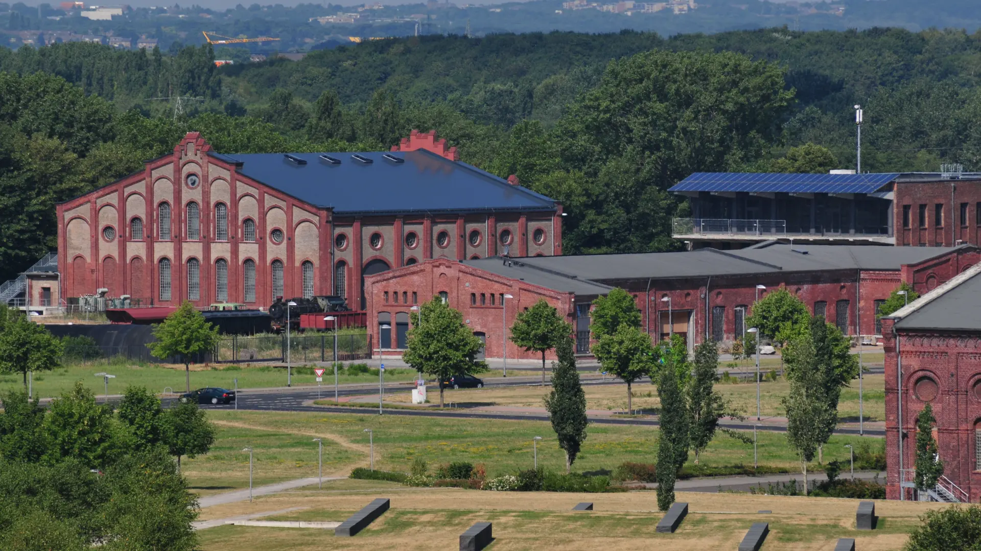 Foto: Ansicht einer alten Fabrikanlage mit mehreren Gebäuden aus roten Ziegelsteinen