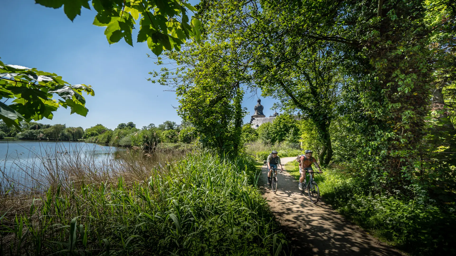 Zwei Radfahrer in der Natur zwischen Wäldern und einem See