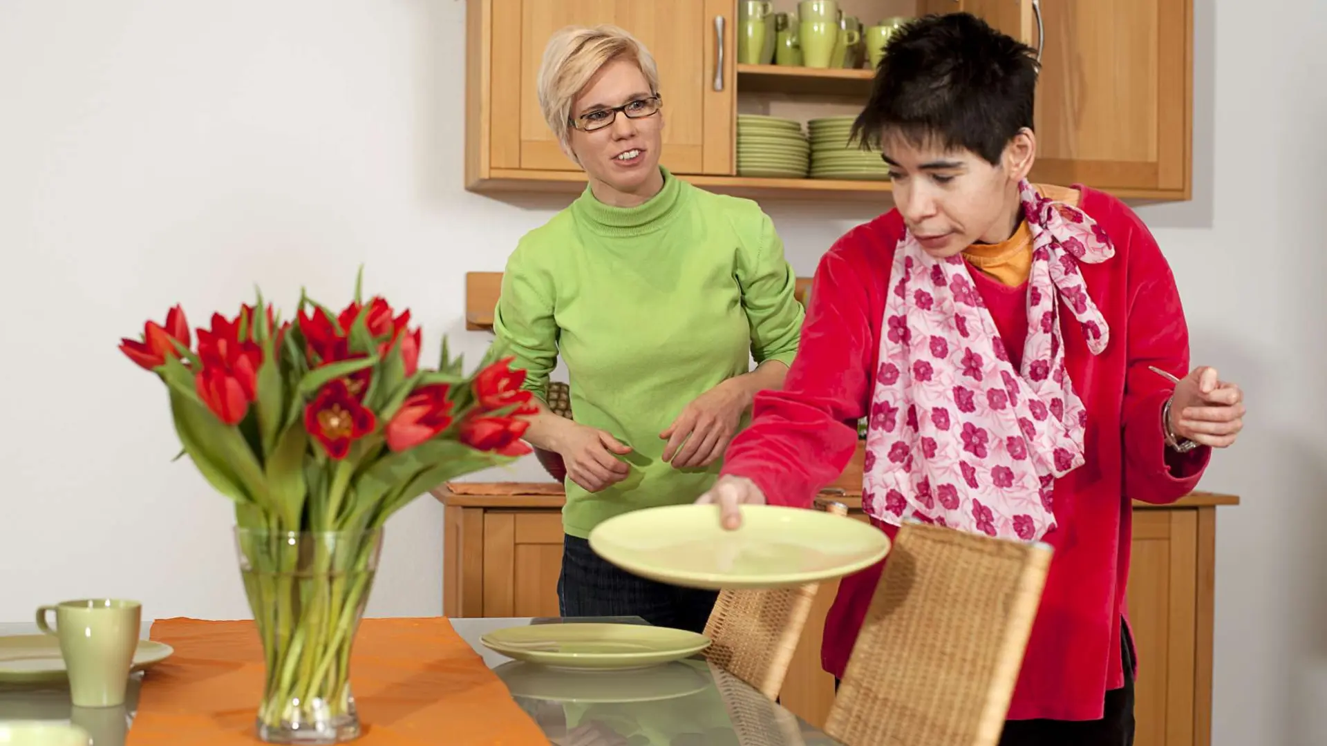 Frau mit Assistenzkraft beim Tisch decken