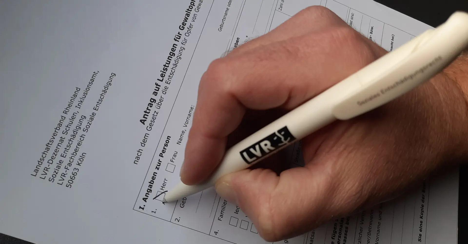 Eine Hand mit Stift beim Ausfüllen eines Antrags