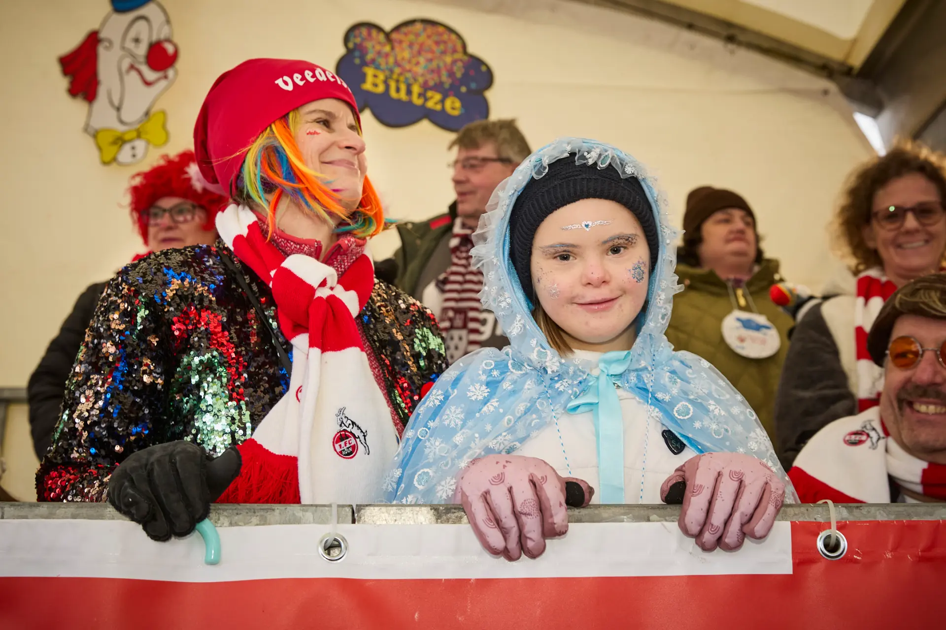 Ein Mädchen in einem hellblauen Kostüm lächelt freundlich. Sie steht auf der Tribüne beim Kölner Rosenmontagszug.