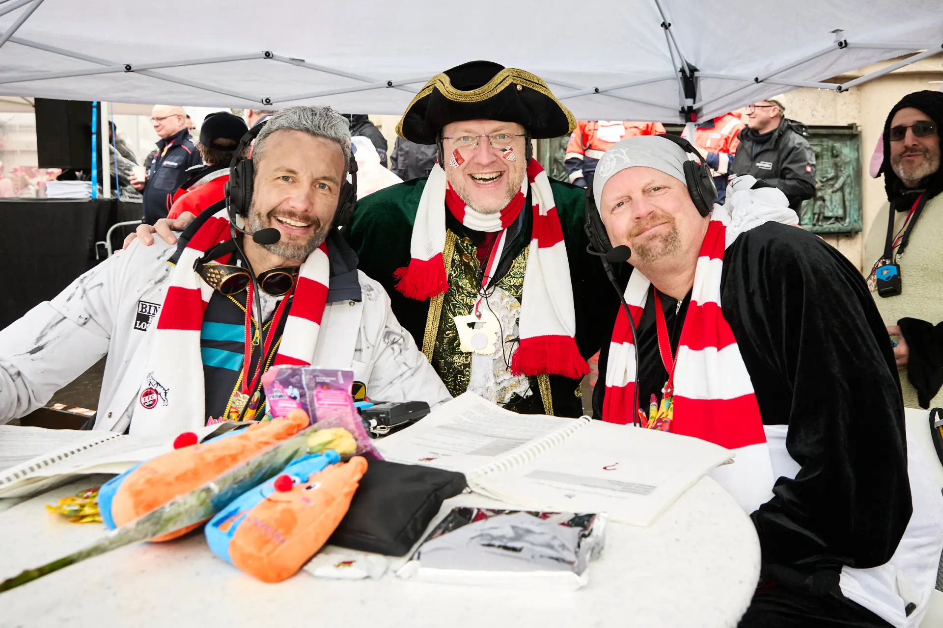 Drei verkleidete Männer mit Mikrofon stehen gemeinsam nebeneinander bei der Blindenreportage des Kölner Rosenmontagszugs.