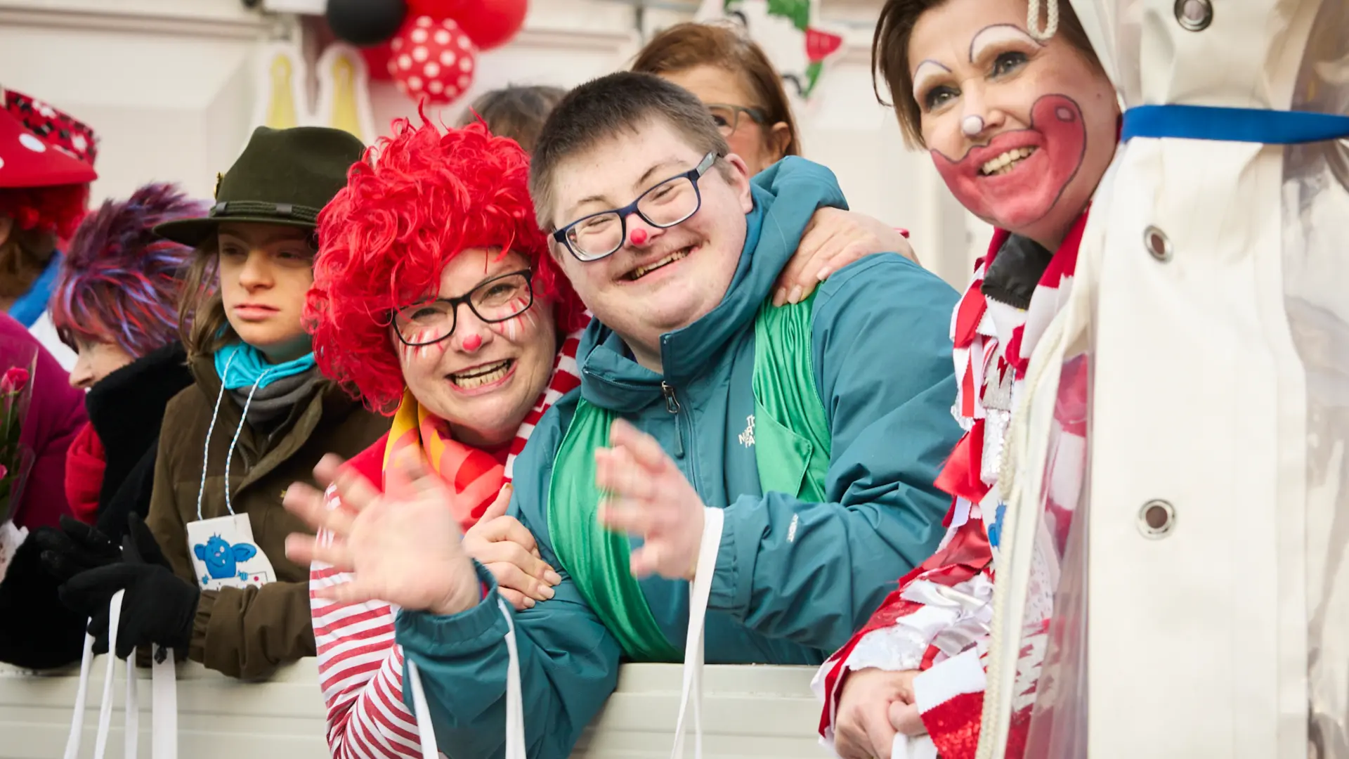 Drei fröhliche Menschen mit und ohne Behinderung klatschen in die Hände bei den Schull un Veedelzöch 2026.