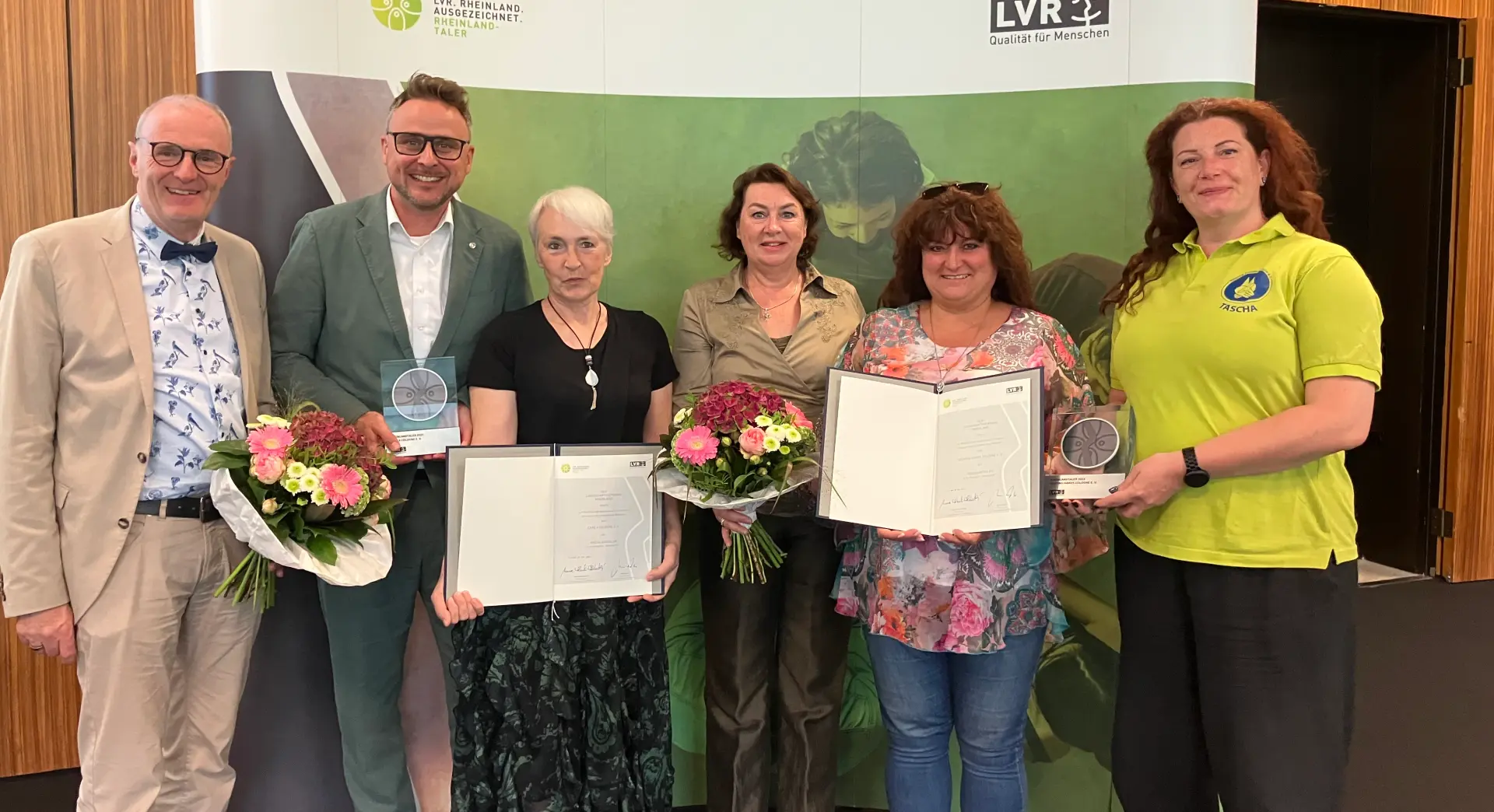 Ein Gruppenfoto. Zwei Frauen halten eine Urkunde in der Hand. Zwei weitere Personen halten Trophäen.