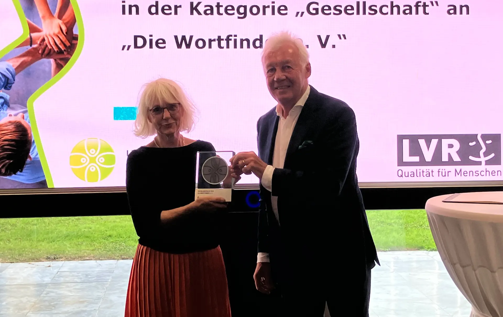 Ein Mann übergibt einer Frau eine Trophäe.