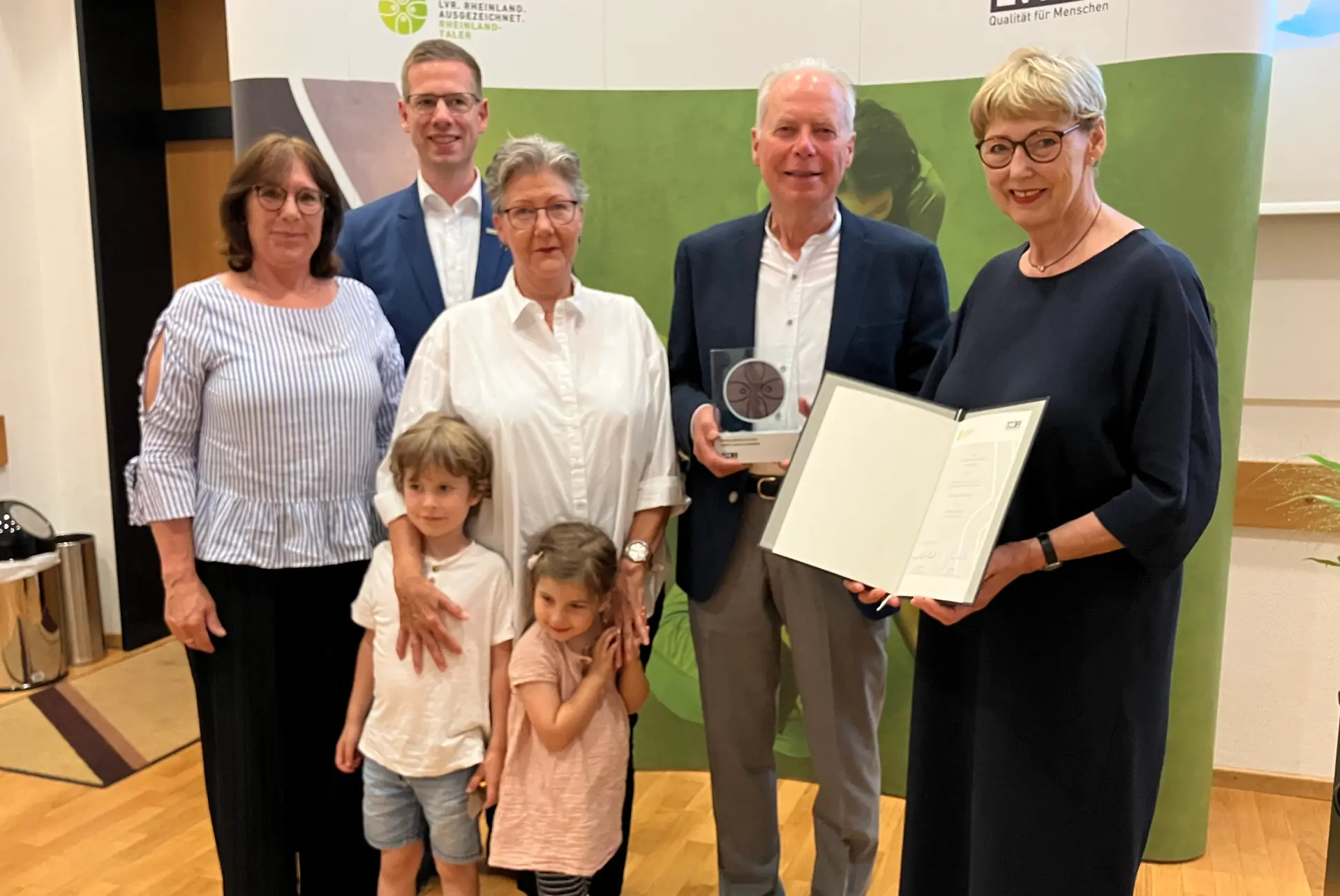 Eine Gruppenfoto. Die Frau rechts hält eine Urkunde in der Hand. Der Mann links daneben hält eine Urkunde.