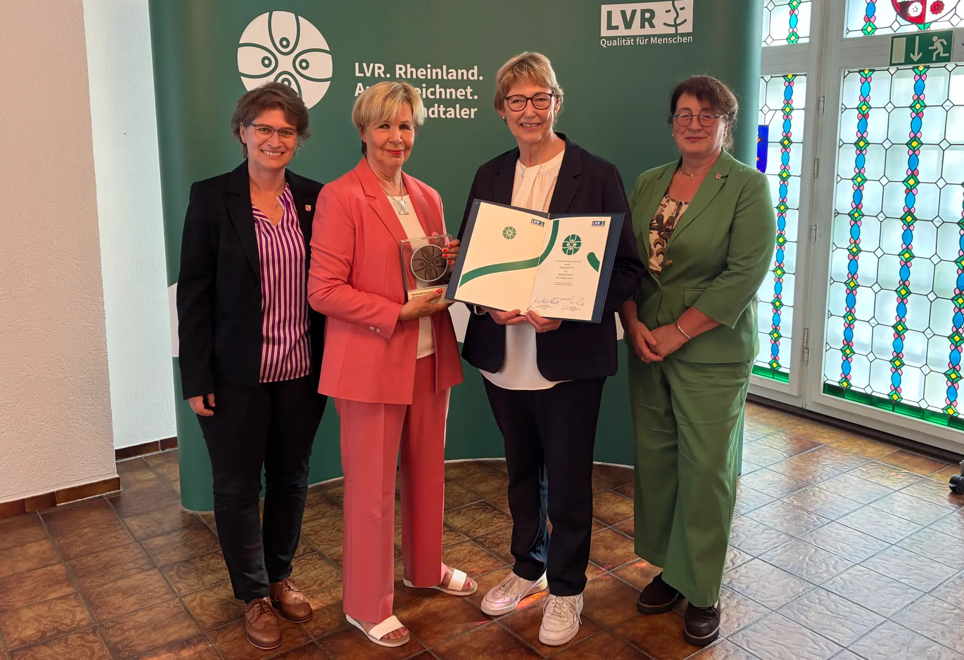 Ein Gruppenfoto von vier Frauen. Die zweite Frau von links hält eine Trophäe in der Hand.