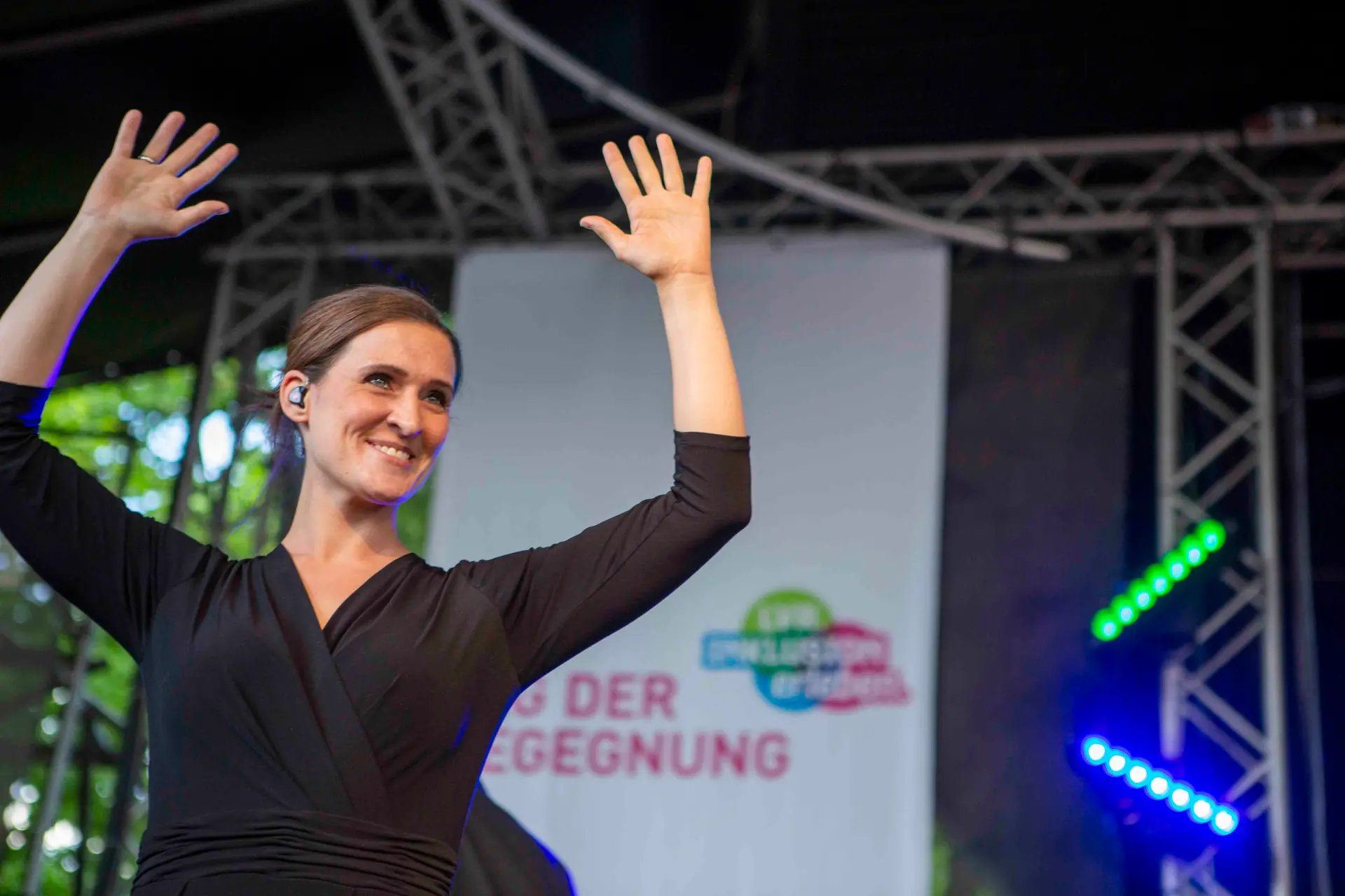 Das Bild zeigt eine Geärdensprachdolmetscherin beim "Tag der Begegnung". Sie steht auf der Bühne. 