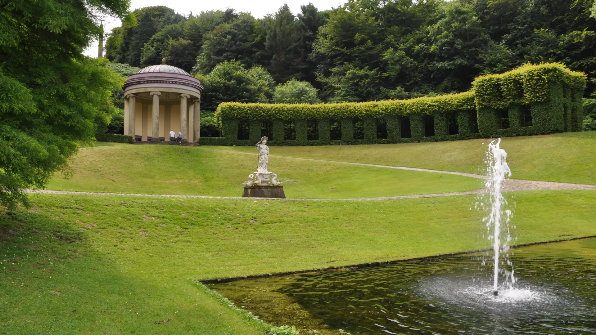 Foto: Gepflegte terrassierte Parkanlage mit Fontaine, Skulptur in der Mitte und im Hintergrund ein Pavillion.  