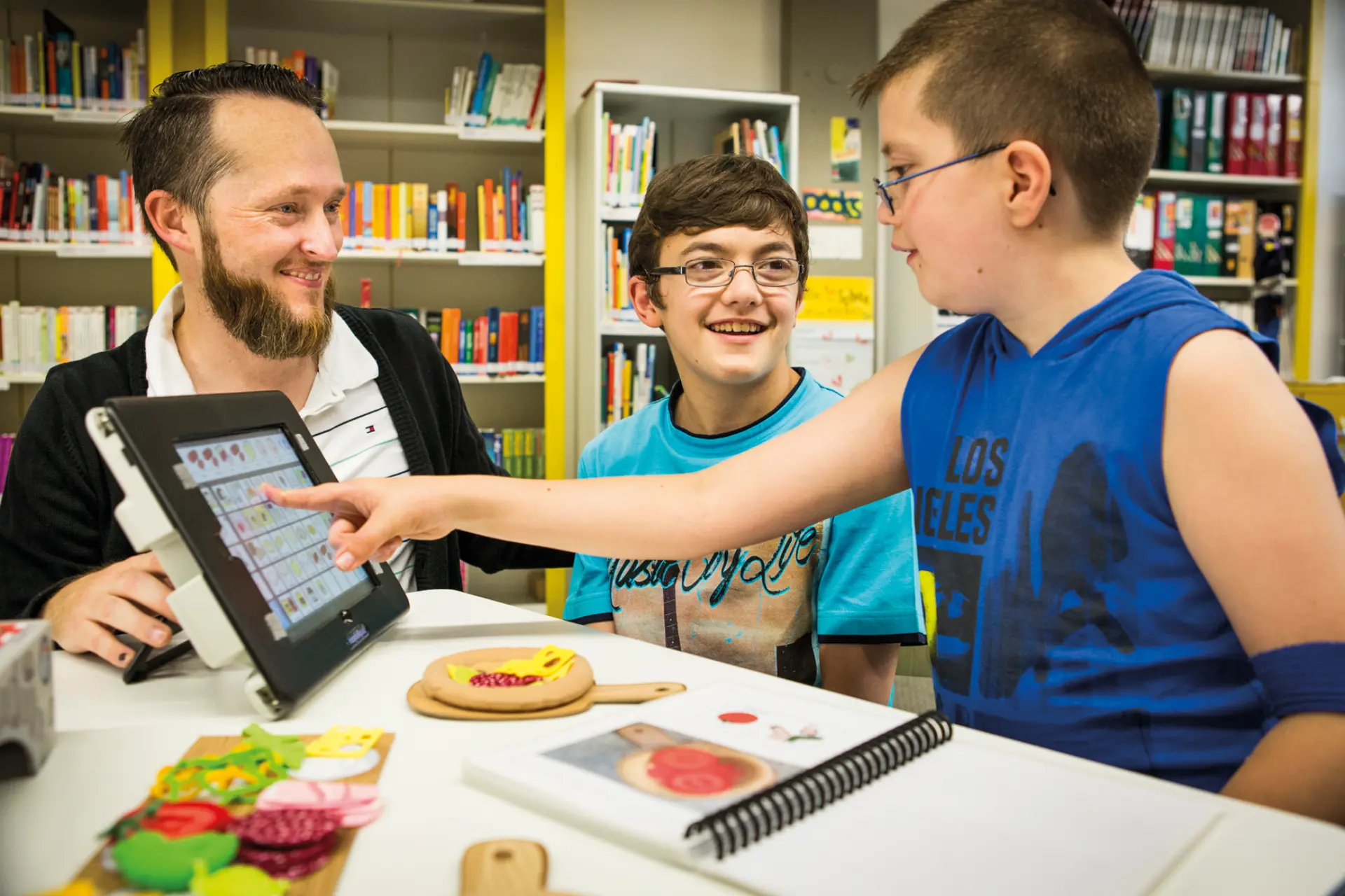 Zwei Schüler mit Sehbehinderung und ein Lehrer mit Hilfsmittel 