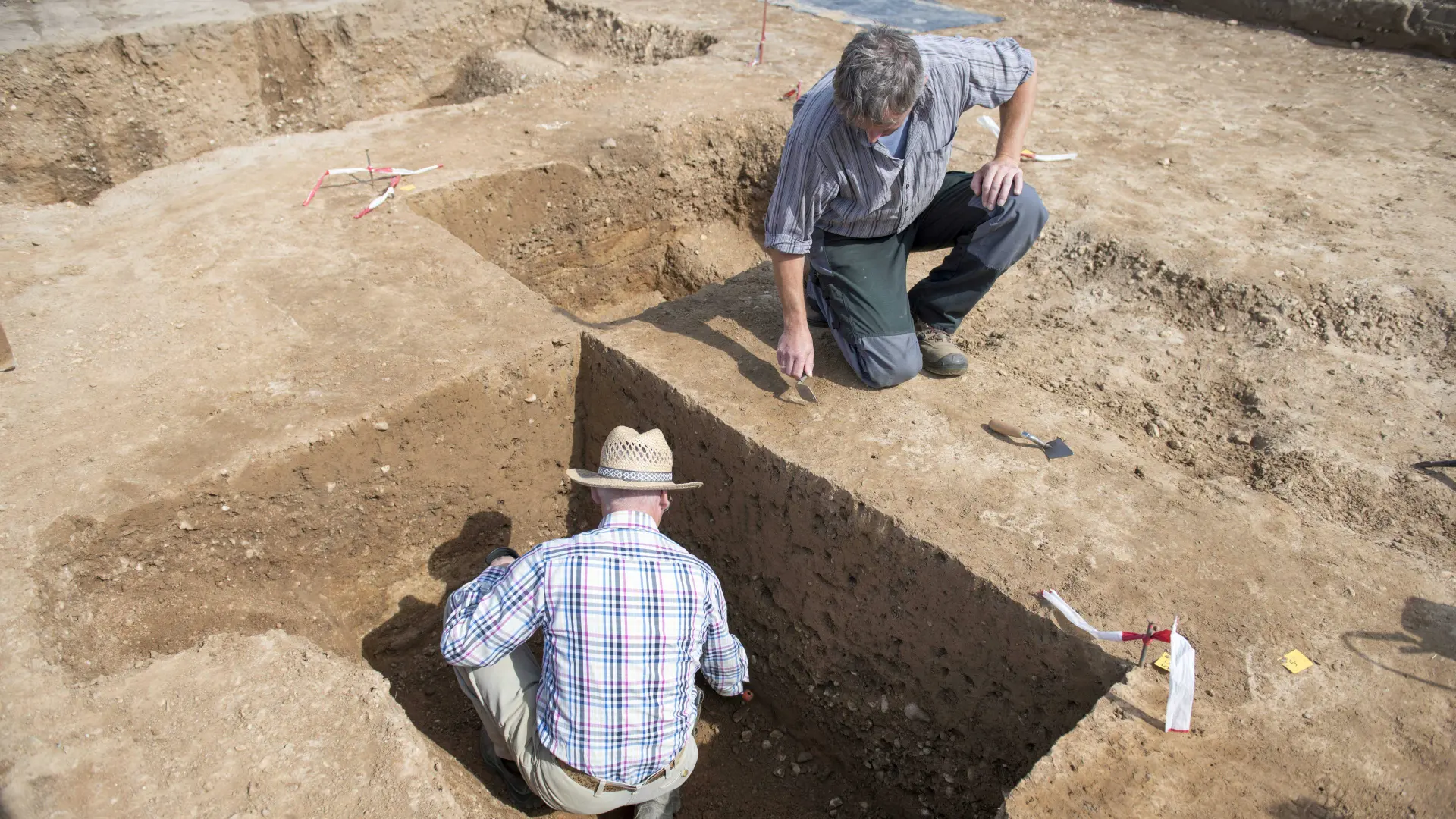 Foto: zwei Männer arbeiten in einer archäologischen Grabung.