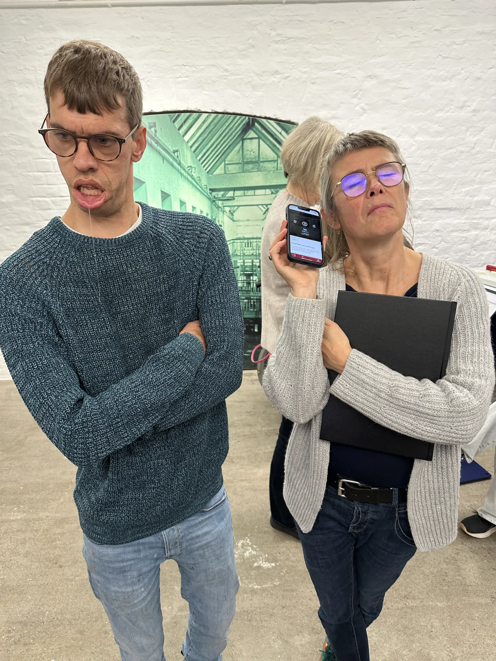 Ein Mann und eine Frau hören dem Audioguide der LVR-Gedenkstätte Brauweiler zu.