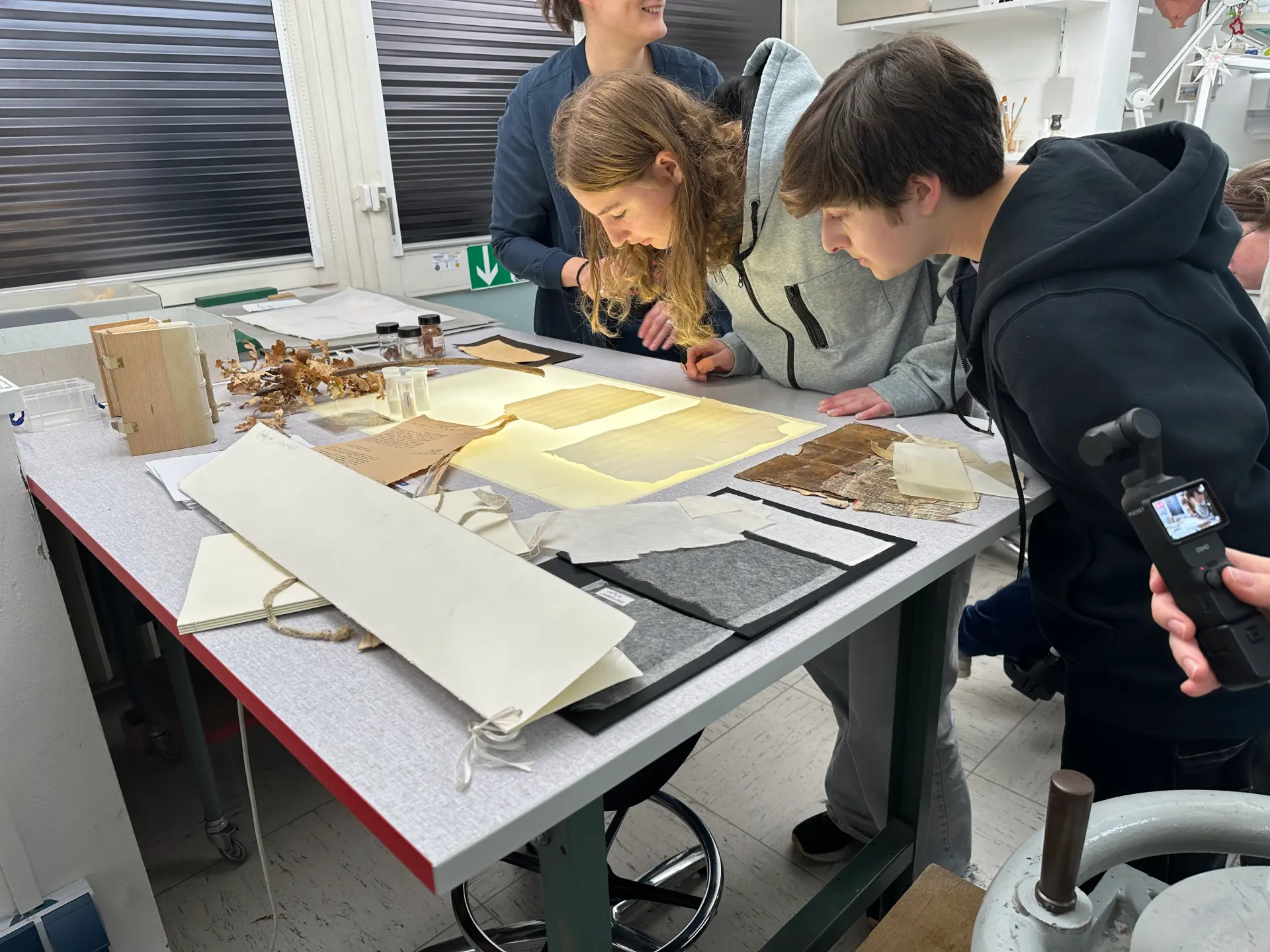 Zwei junge Frauen beugen sich über einen von unten beleuchteten Tisch mit Papier darauf.