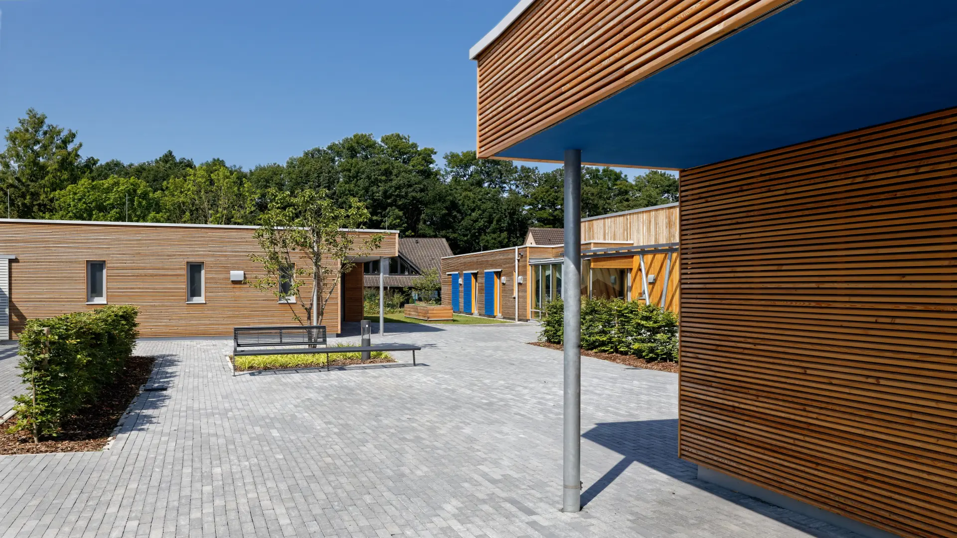 Ansicht LVR- Kindergarten in Holzbauweise mit Spielgeräten im Vordergrund
