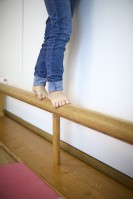 Bildausschnitt von Kinderbeinen, die auf einem Balken balancieren