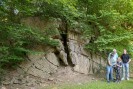 Drei Erwachsene und ein Kind stehen vor einer Felswand, welche von grünen Blättern umgeben ist.
