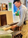 Ein Mann schiebt eine Holzlatte in eine Maschine.